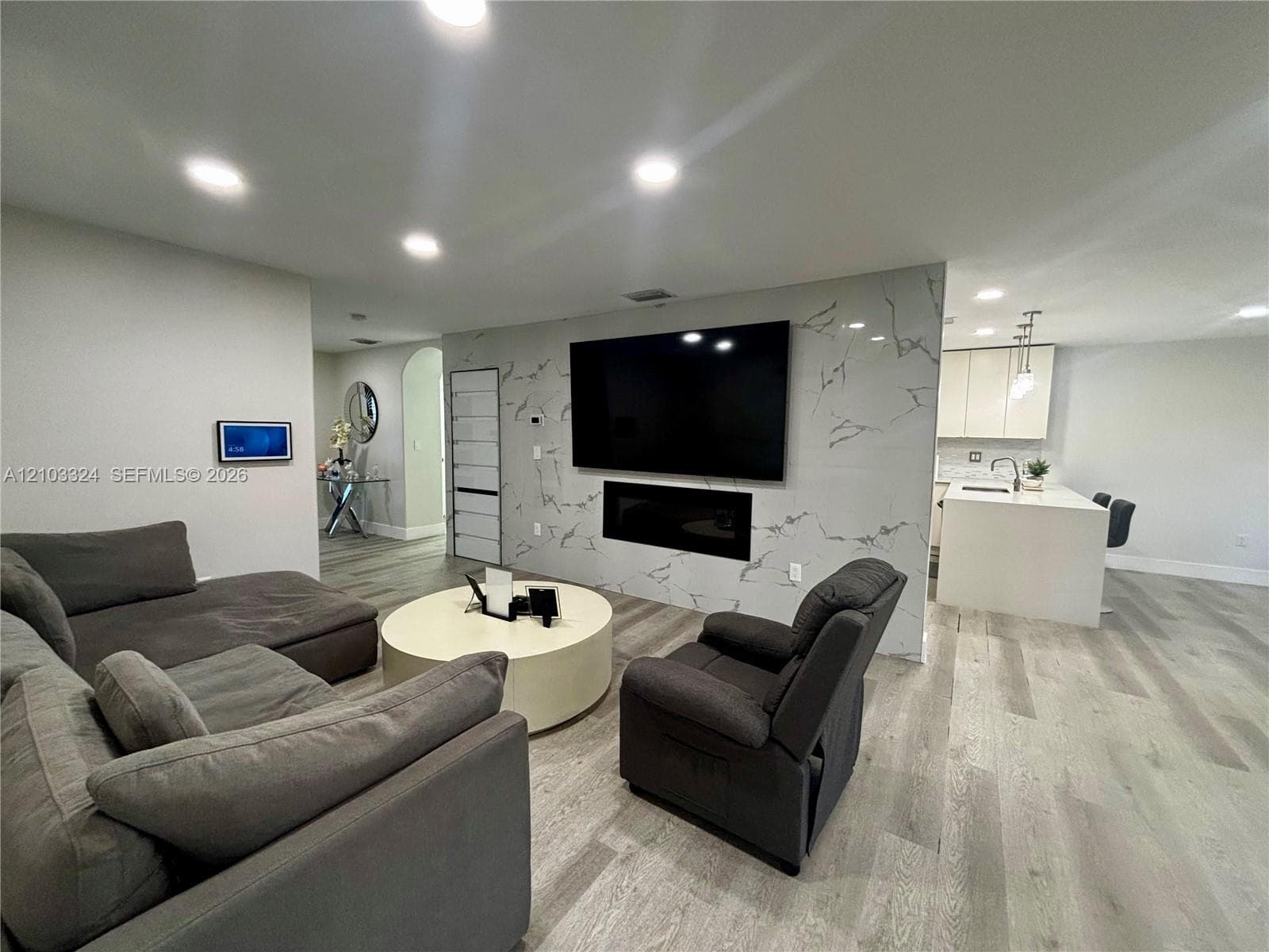 Living area featuring a floor-to-ceiling stone-veneer accent wall, a built-in electric fireplace, recessed lighting, and wood-finish flooring