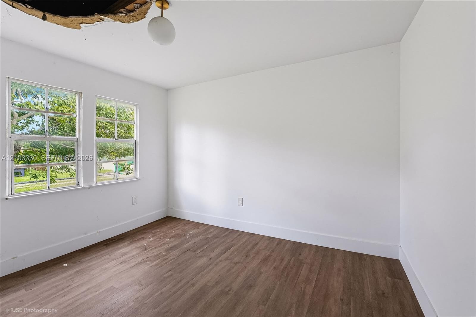 Interior space featuring wood-finish flooring, dual windows with grid muntins, and a globe pendant light fixture
