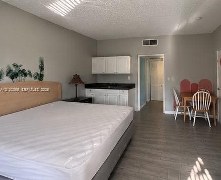 Interior space featuring wood-finish flooring, white cabinetry with dark countertops, and a built-in sink