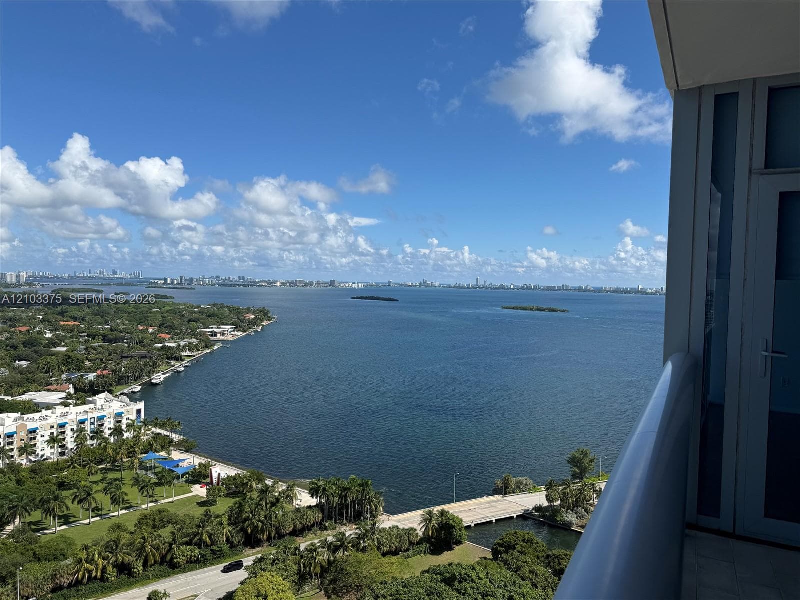Elevated balcony with a solid metal railing, featuring expansive water and coastal scenery