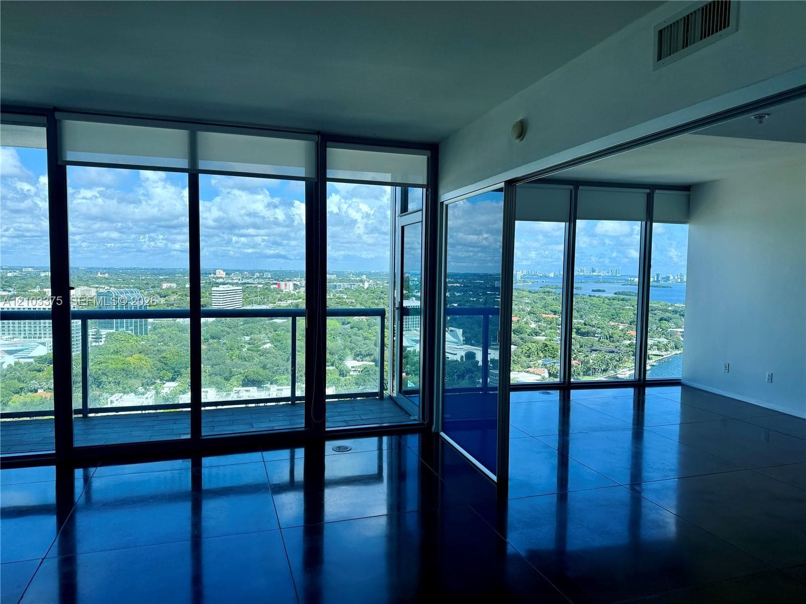 Floor-to-ceiling glass windows, polished concrete flooring, expansive balcony, and panoramic exterior scenery