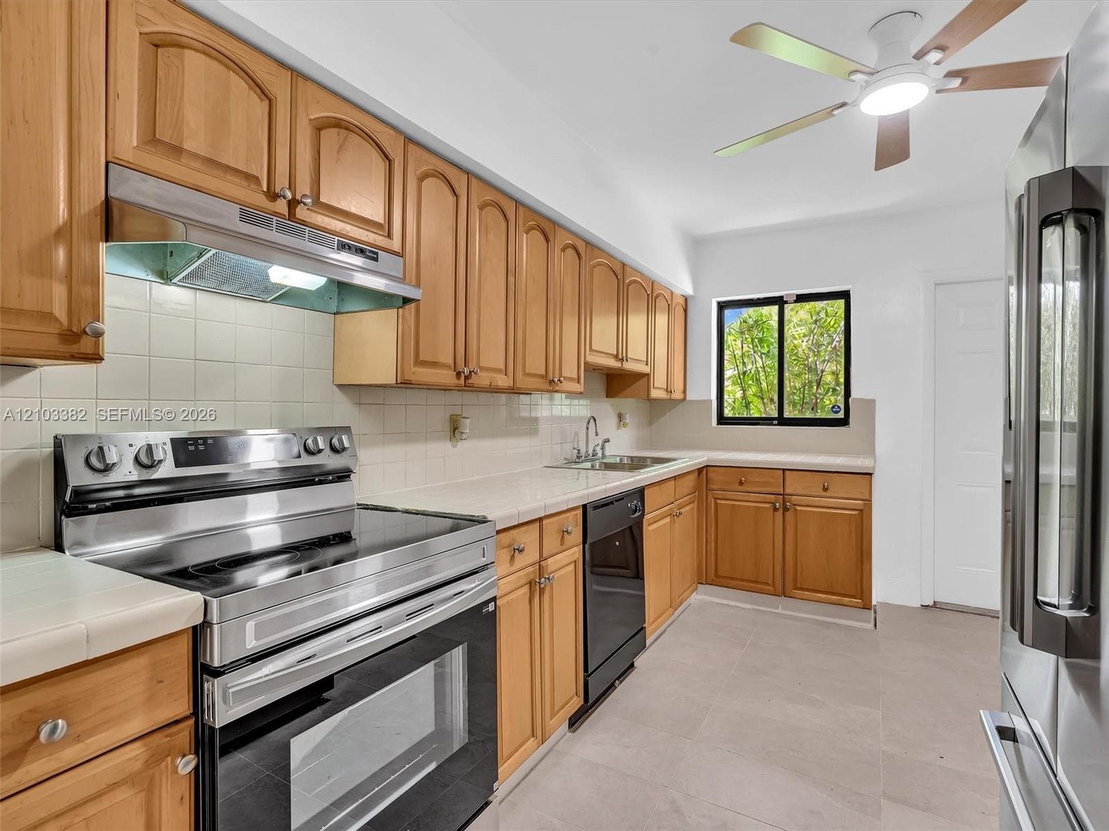 Spaceous kitchen featuring tile countertops, stainless steel appliances, a ceiling fan with integrated lighting, and tile flooring. House for rent in Coral Gables. House for rent listed by Realtor.