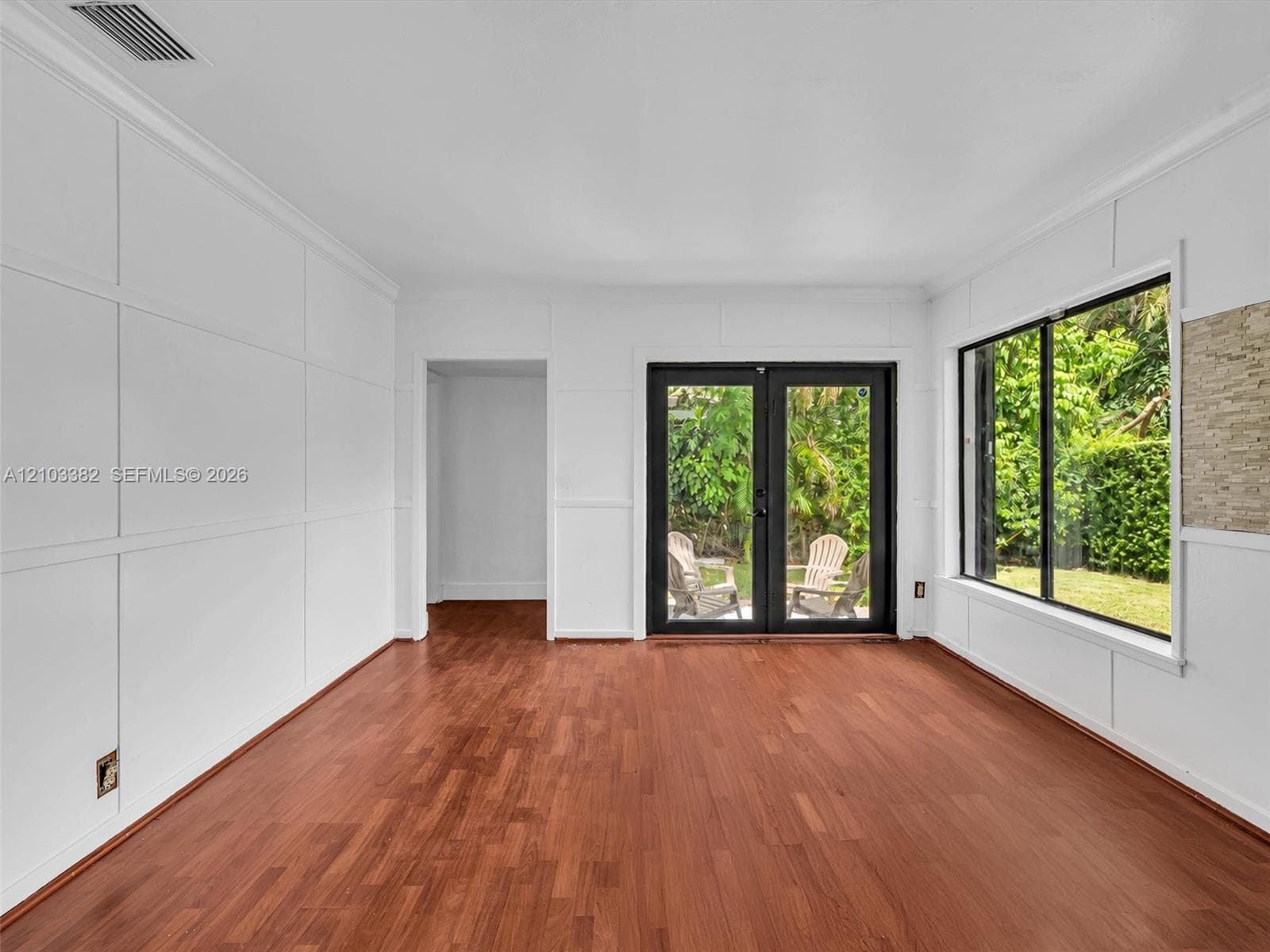 Awesome Florida room featuring wood-finish flooring, custom wall paneling, expansive windows, and black-framed double doors. House for rent in Coral Gables. House for rent listed by Realtor