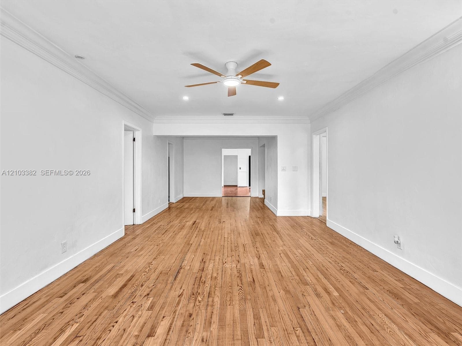 Sunny living room and dining room featuring wood-finish flooring, crown molding, recessed lighting, and ceiling fans. Home has a split design, separating the 4 bedrooms. House for rent in Coral Gables. House for rent listed by Realtor