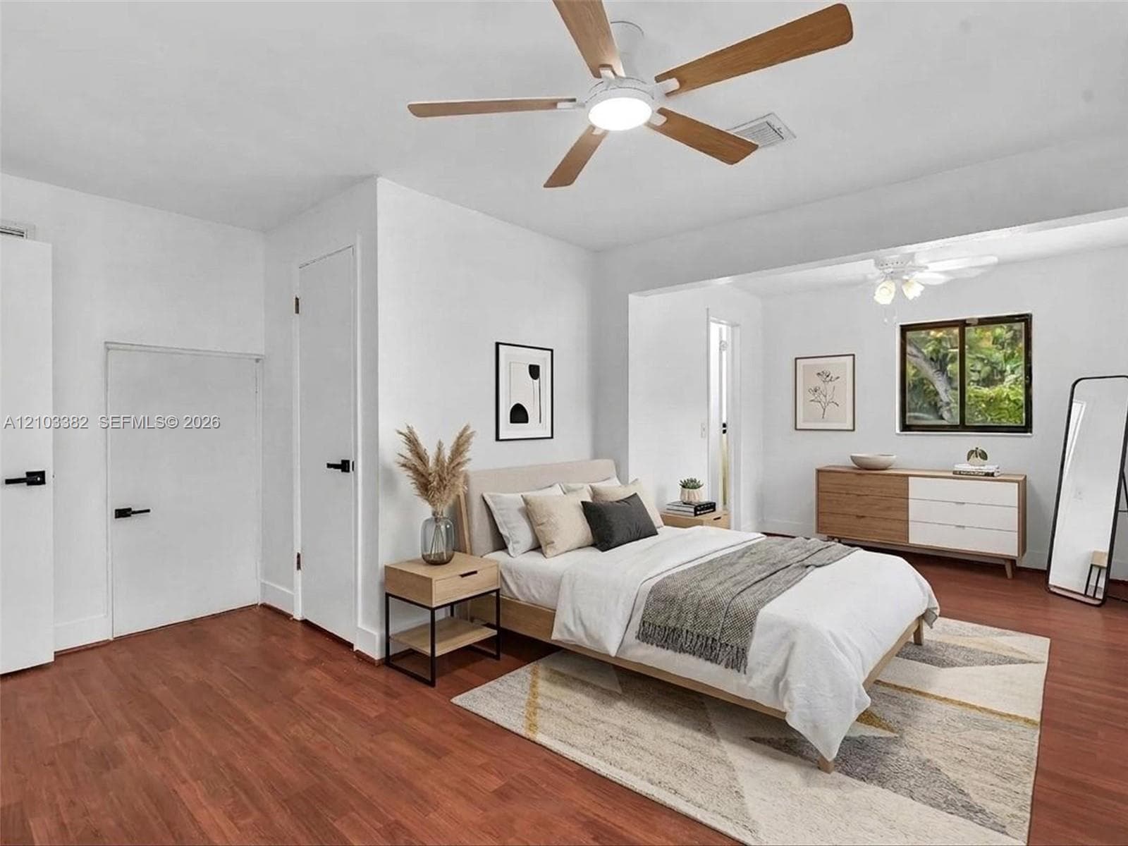 VIRTUAL STAGING. Rear private bedroom featuring walk-in closet, en-suite bath, siting area and wood-finish flooring, white doors with matte black hardware, dual ceiling fans, and nice windows. House for rent in Coral Gables. House for rent listed by Realtor.