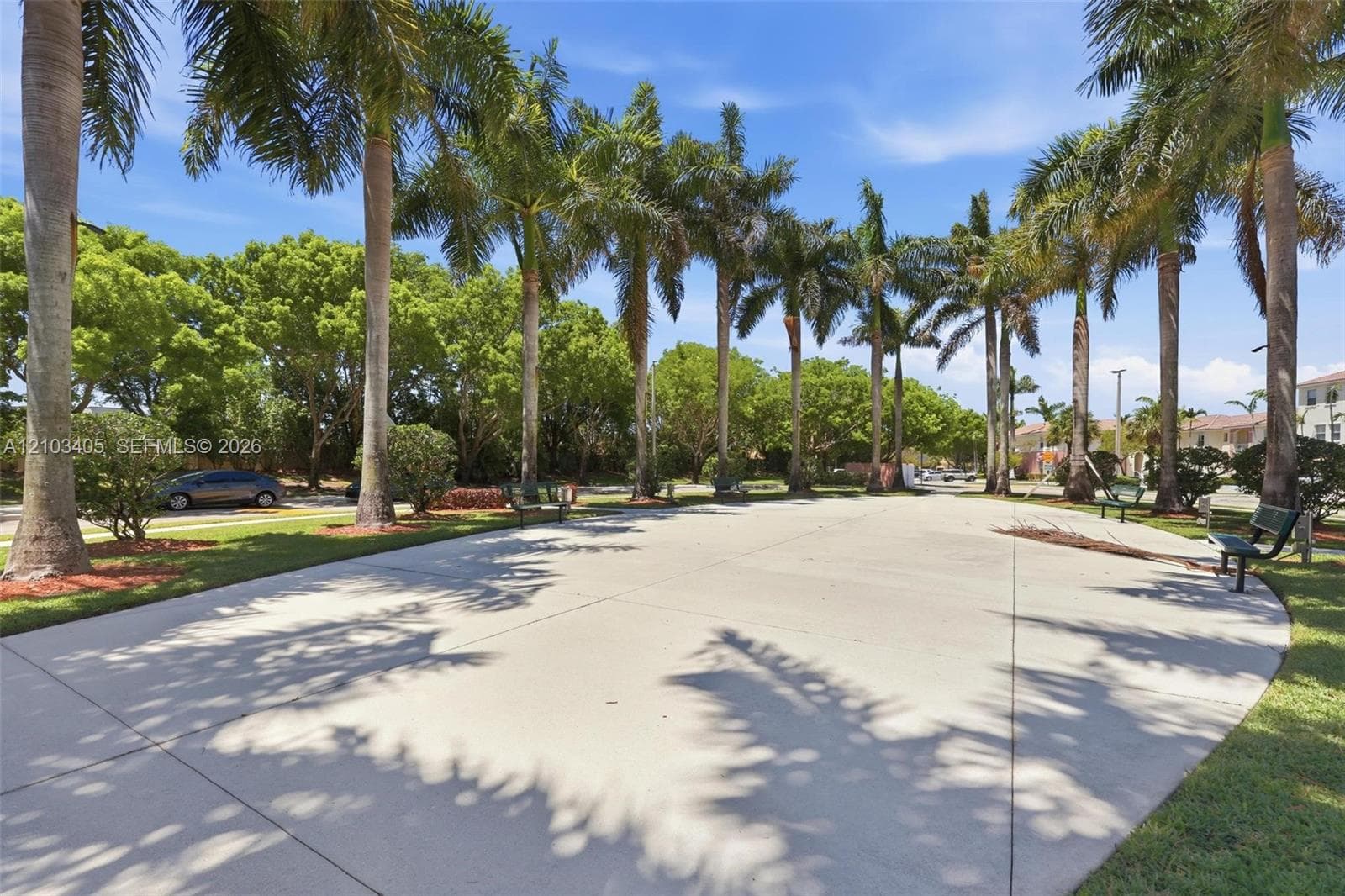 Aerial perspective of a multi-story residential complex featuring stucco siding, clay-tile roofing, and surrounding landscaped grounds with paved walking paths