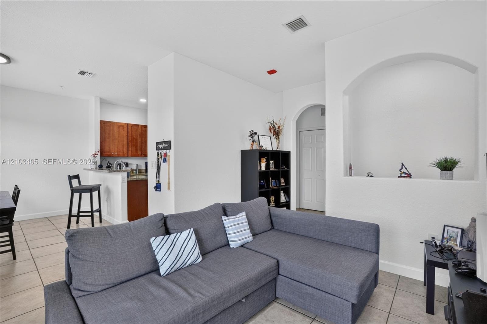 Entryway featuring neutral tile flooring, white six-panel entry door, and double-door closet with white paneled casing