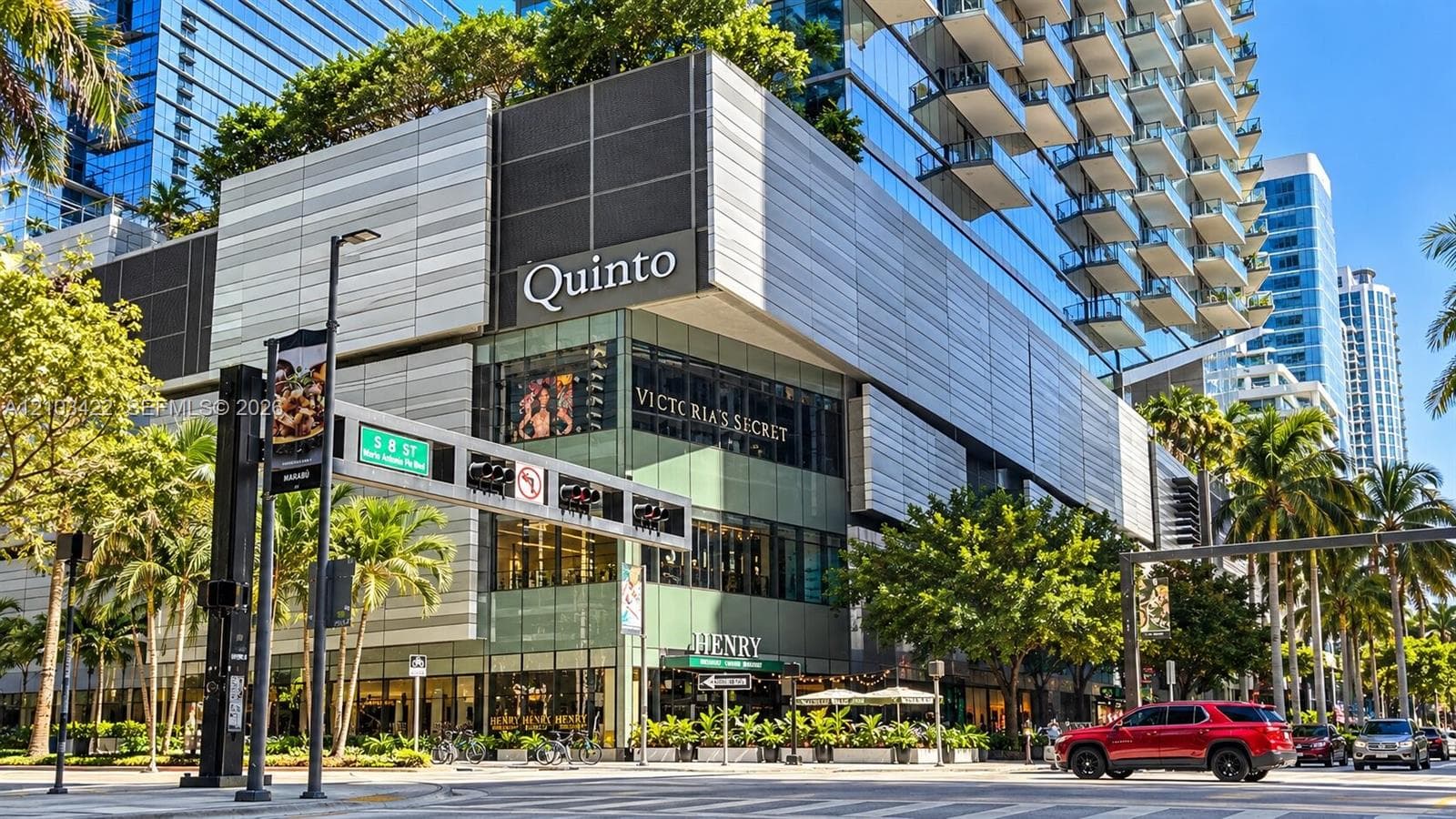 Modern high-rise architecture featuring a multi-story commercial base, integrated retail and dining establishments, extensive glazing, and multiple private balconies