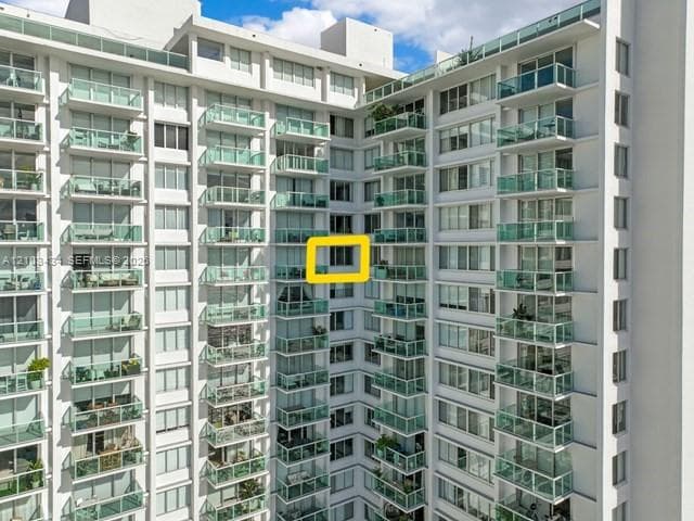High-rise residential exterior featuring white concrete facade, uniform glass balconies, and expansive window lines