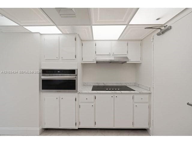 Kitchenette featuring white cabinetry, stone-finish countertops, built-in wall oven, inset stovetop, and stainless steel range hood
