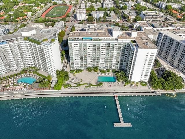 Waterfront high-rise complex featuring multiple swimming pools, a deep-water pier, paved sun decks, and manicured grounds