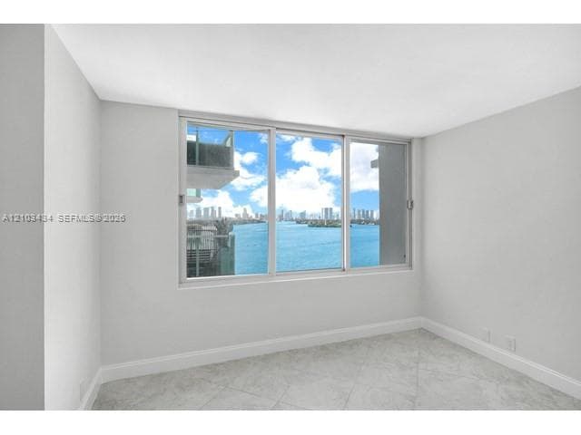 Interior space featuring large-format tile flooring and a expansive window system with water and skyline exposure