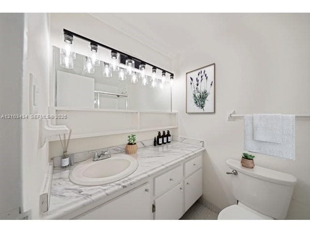 Bathroom featuring a stone-surface vanity countertop, integrated oval sink, white cabinetry with built-in shelving, large wall-mounted mirror, and multi-bulb industrial style lighting fixture