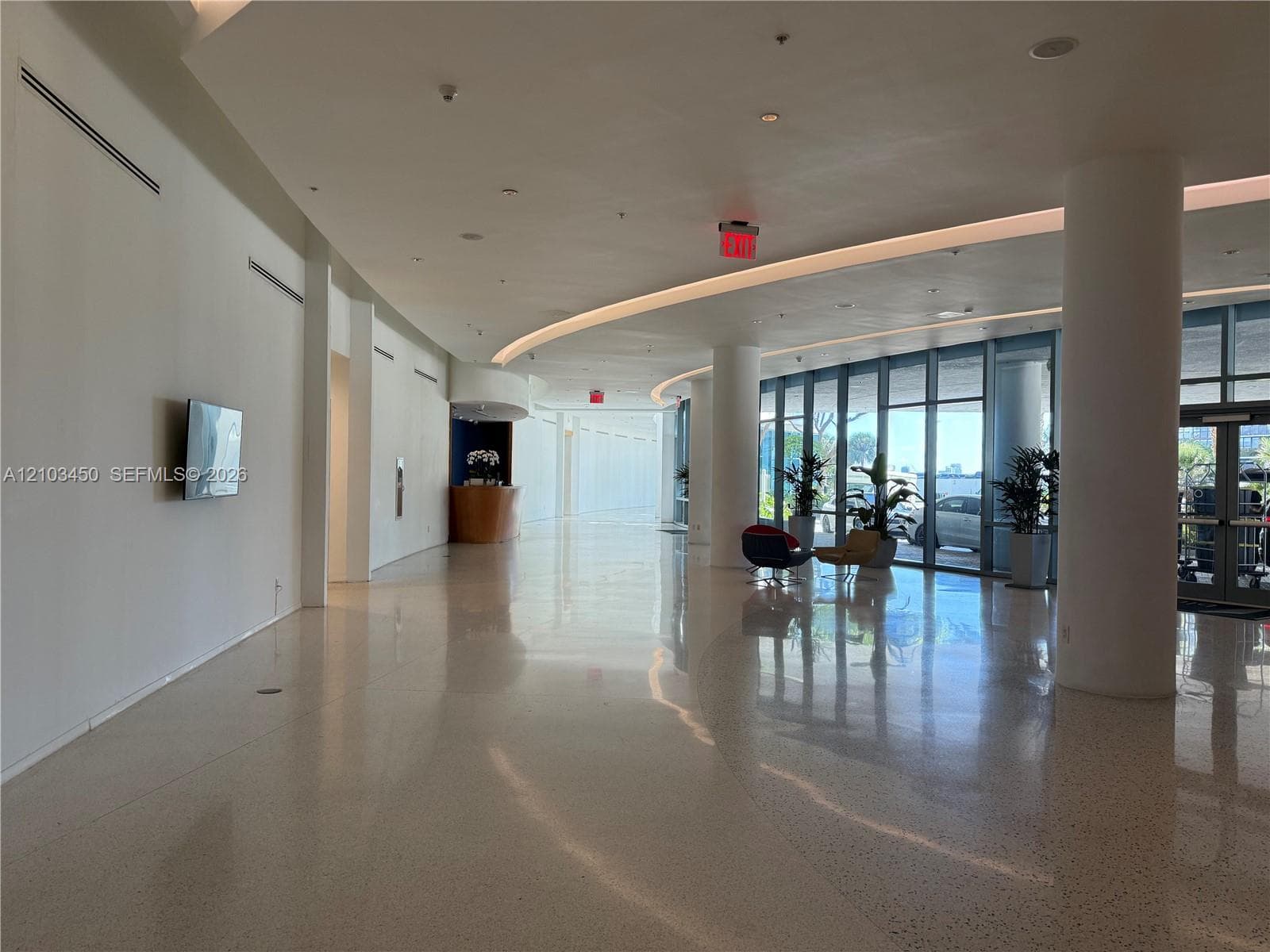 Expansive lobby featuring polished stone flooring, floor-to-ceiling glass paneling, integrated recessed ceiling lighting, and structural support columns