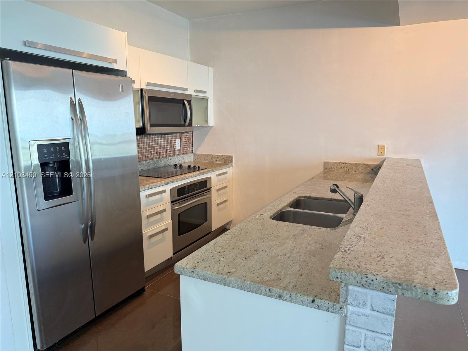 Kitchen featuring white cabinetry, stone-finish countertops, stainless steel appliances, a double-basin sink with a pull-down faucet, and a tiled backsplash