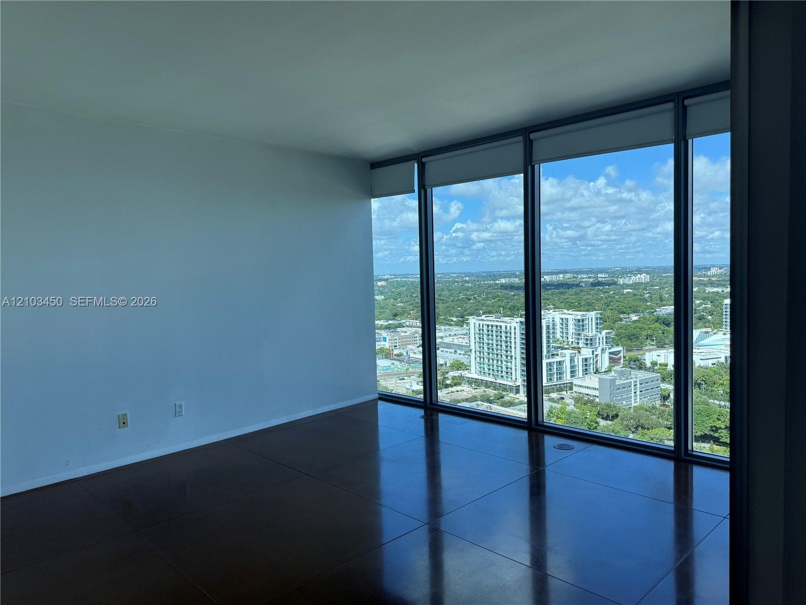 Floor-to-ceiling glass windows, polished concrete flooring, and panoramic urban scenery
