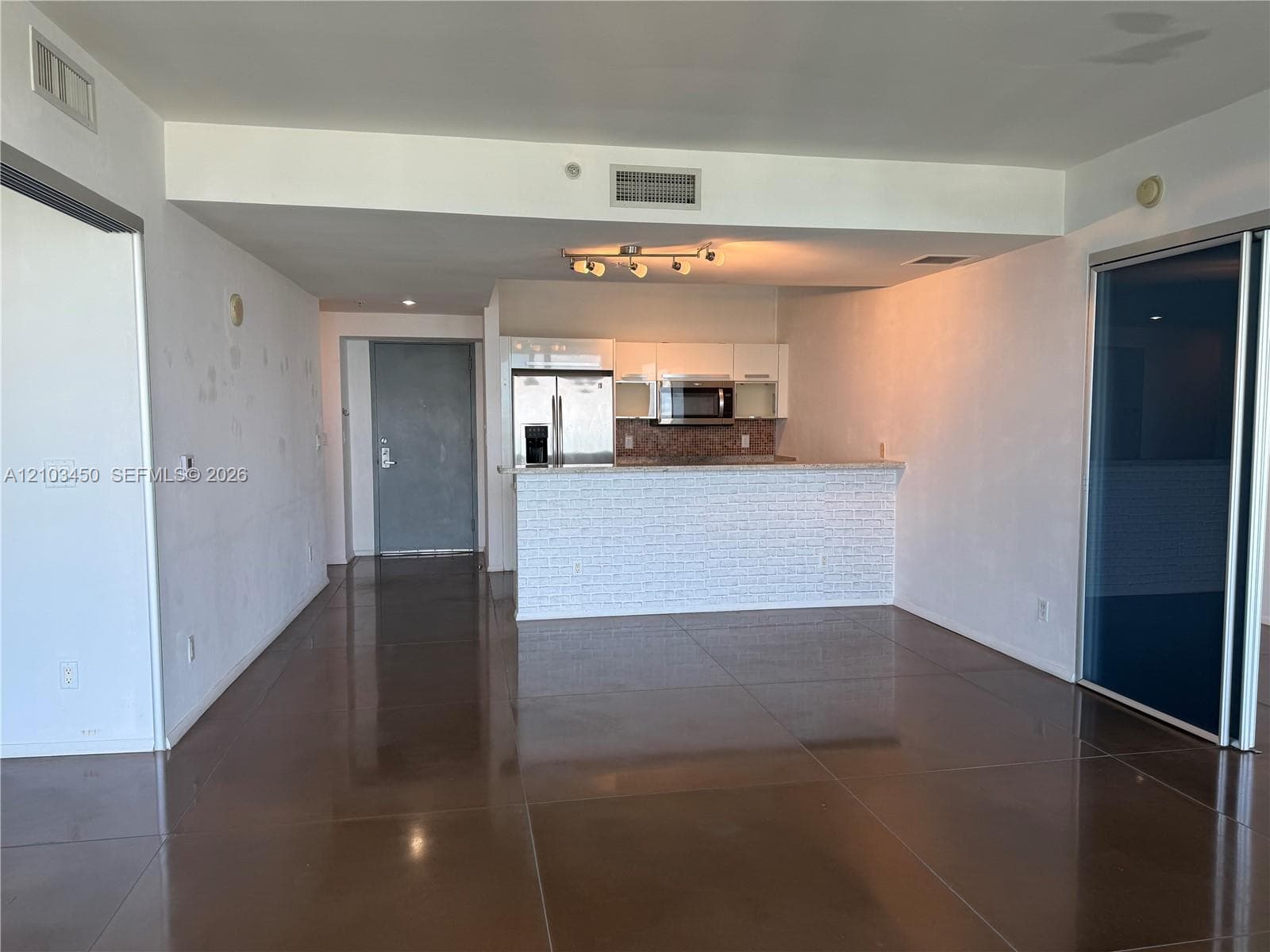 Open floor plan featuring polished concrete flooring, breakfast bar with textured facing, and recessed lighting