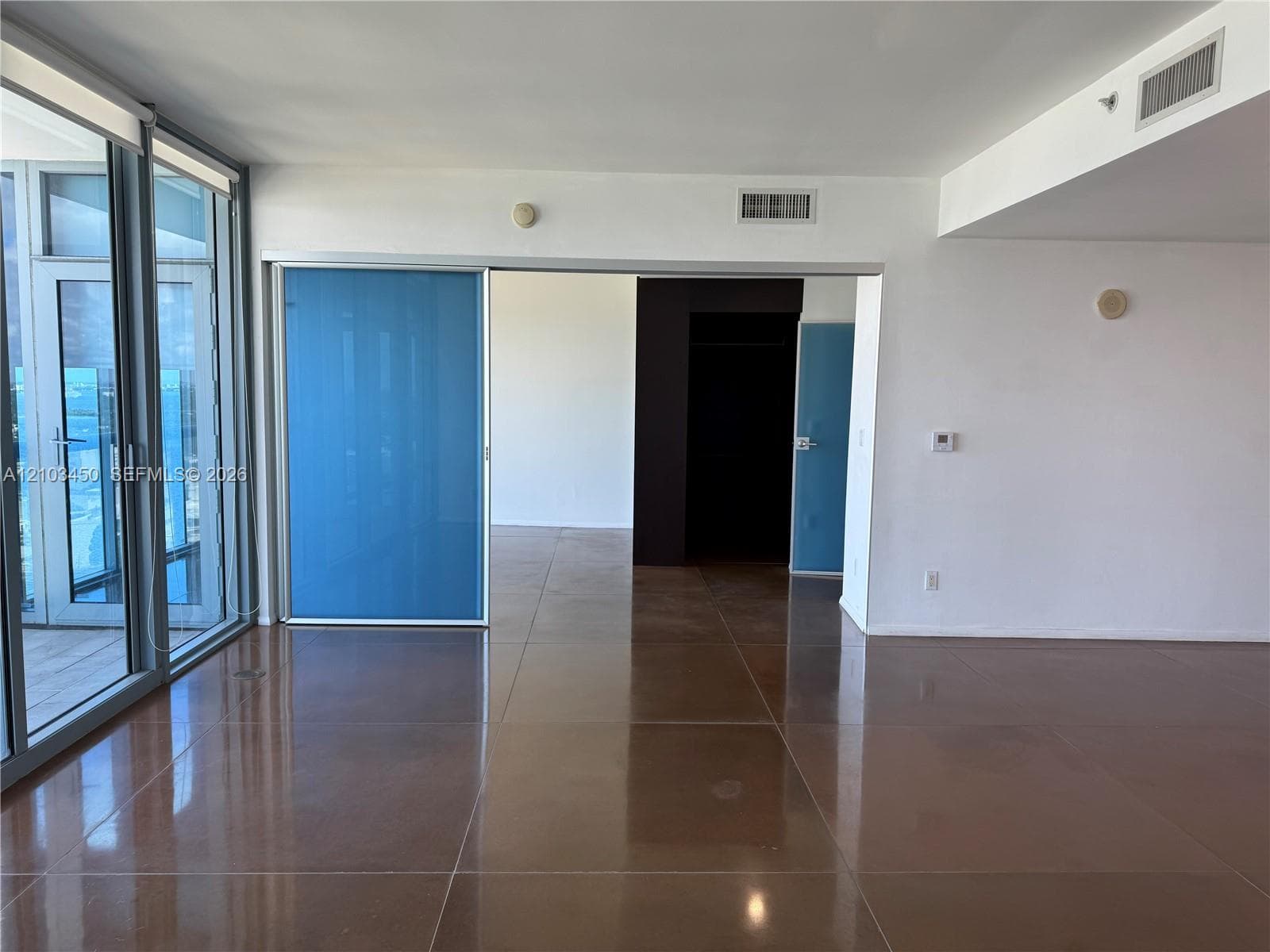 Polished concrete flooring, floor-to-ceiling glass wall with sliding door access, and translucent blue panel room partition