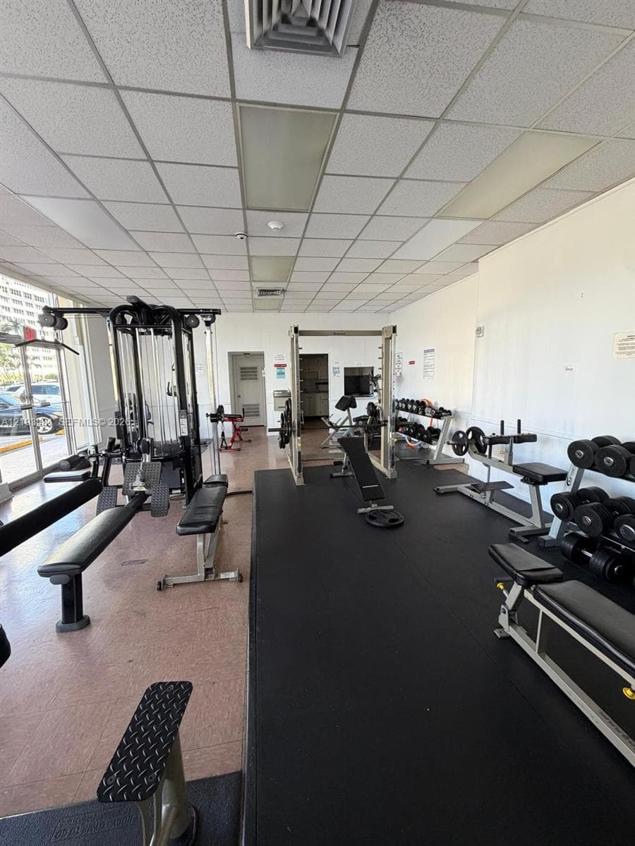 Fitness space featuring a drop ceiling, expansive floor-to-ceiling windows, and integrated rubberized flooring