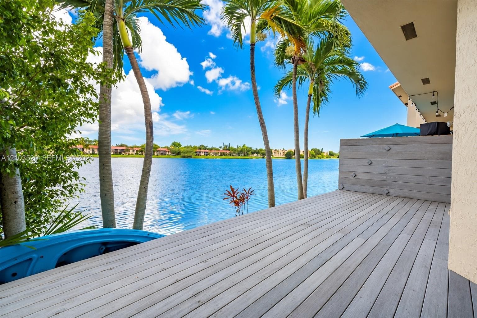 Waterfront wood-finish deck with a privacy screen, recessed lighting, and integrated palm trees
