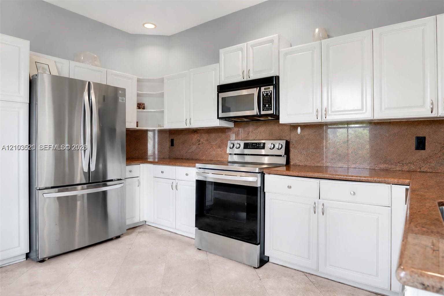 Kitchen featuring white cabinetry, stone countertops, stone backsplash, stainless steel refrigerator, and stainless steel range