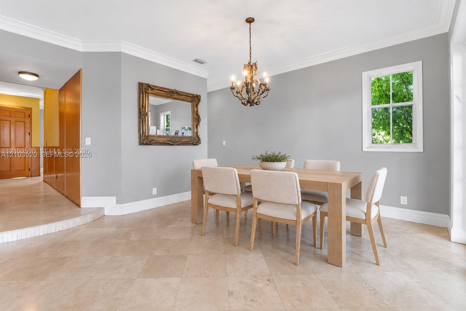 Neutral-toned walls featuring crown molding, overhead chandelier lighting, tile flooring, and multi-lite windows