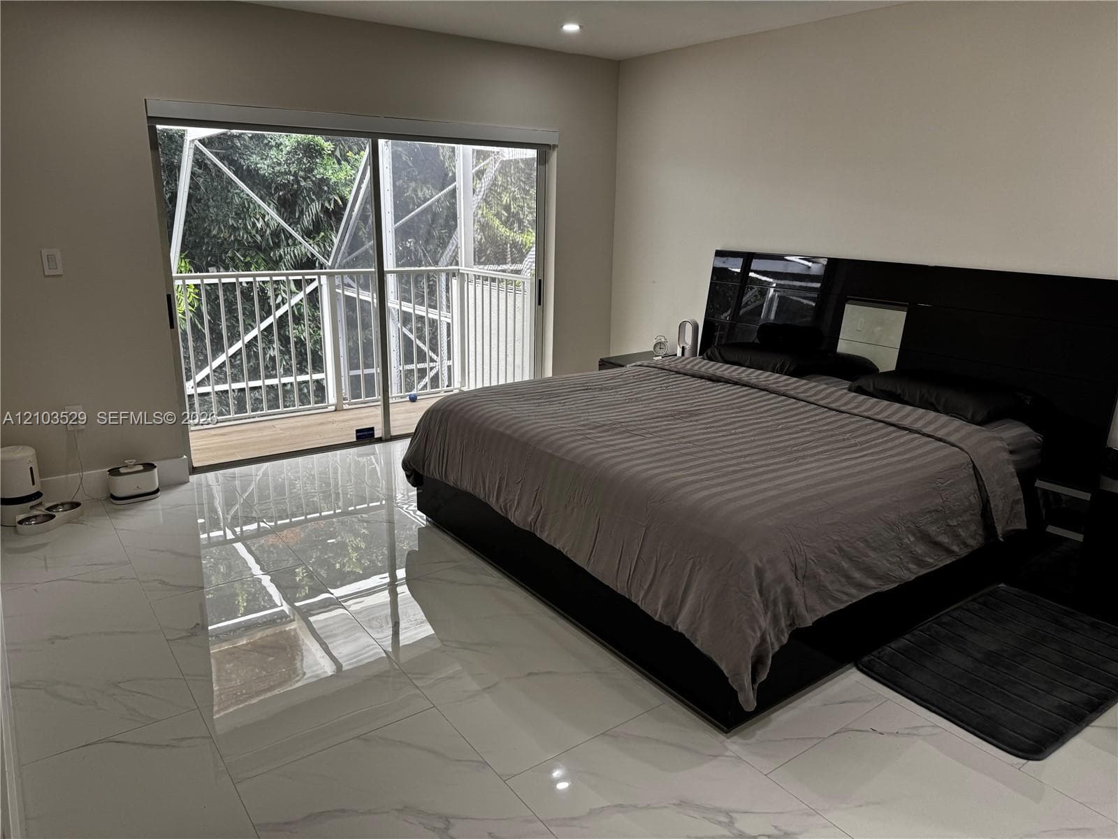 Polished stone-look tile flooring, recessed ceiling lighting, and sliding glass doors opening to a screened balcony
