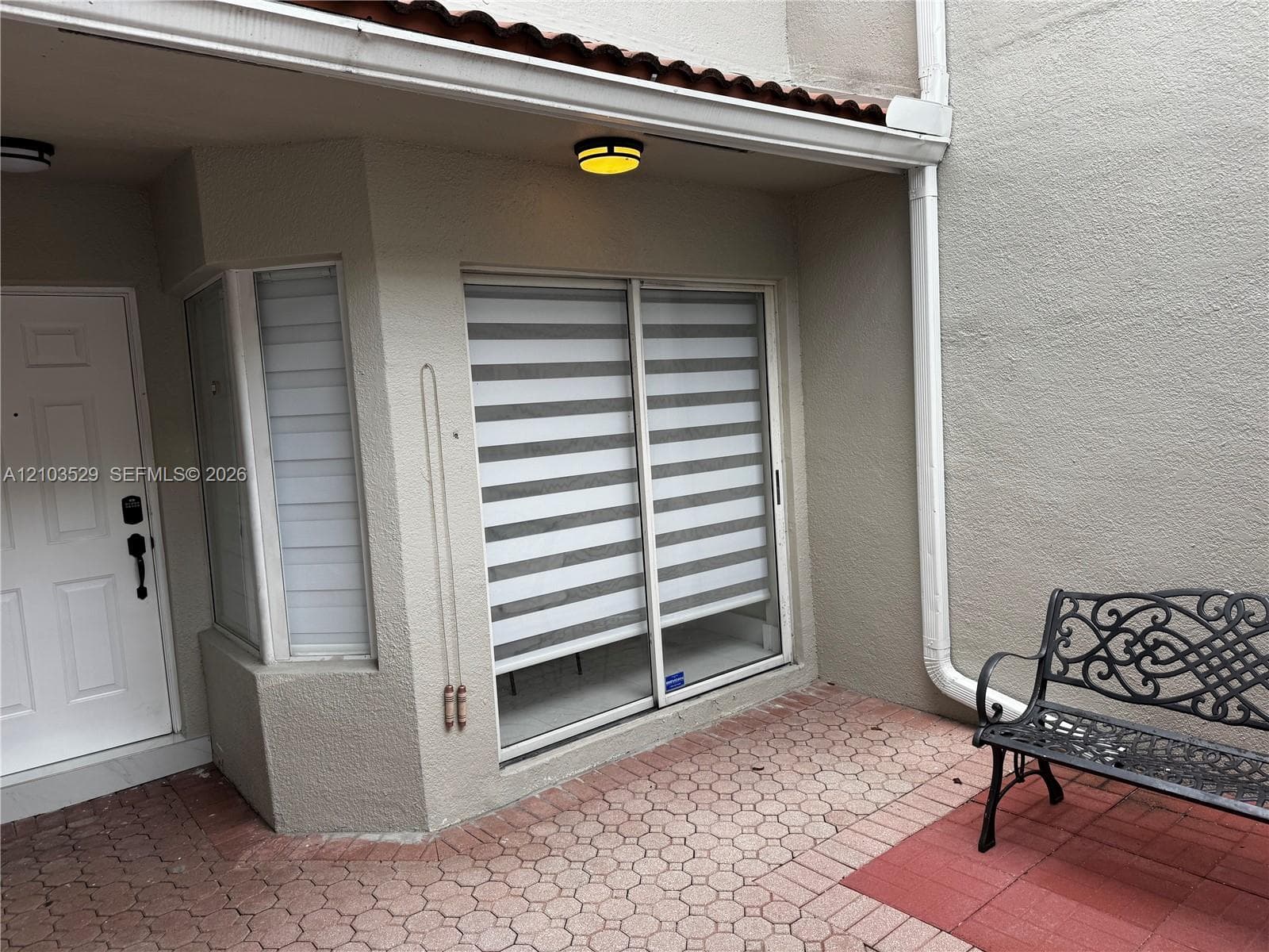 Stucco exterior with a paver patio, sliding glass door, and a solid-core panel door