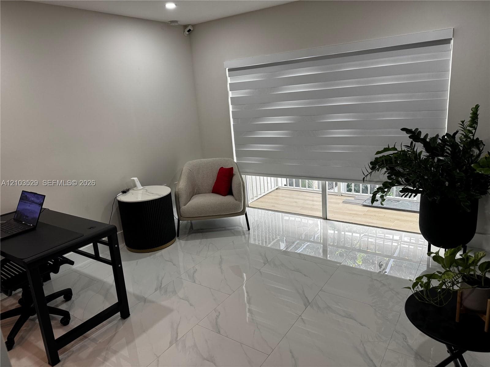 Large-format tile flooring with a neutral veined finish, floor-to-ceiling glass sliding doors, and adjustable dual-layer roller shades
