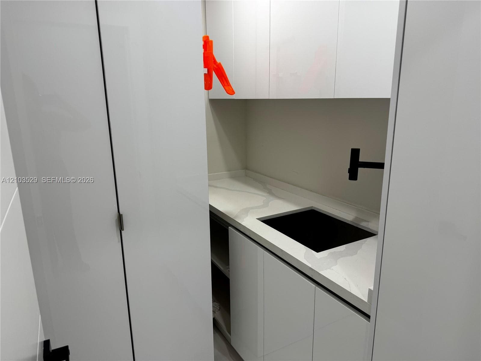 White cabinetry featuring stone-finish countertops, an undermount sink, and matte black hardware