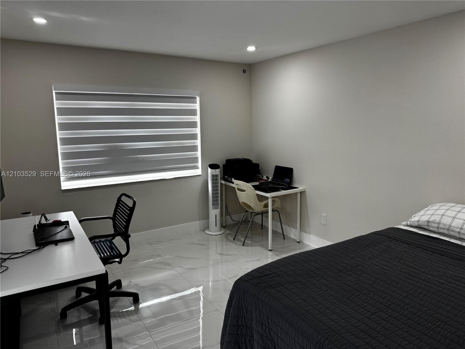 Neutral-toned interior featuring large-format polished tile flooring, recessed lighting, and a dual-shade roller window treatment