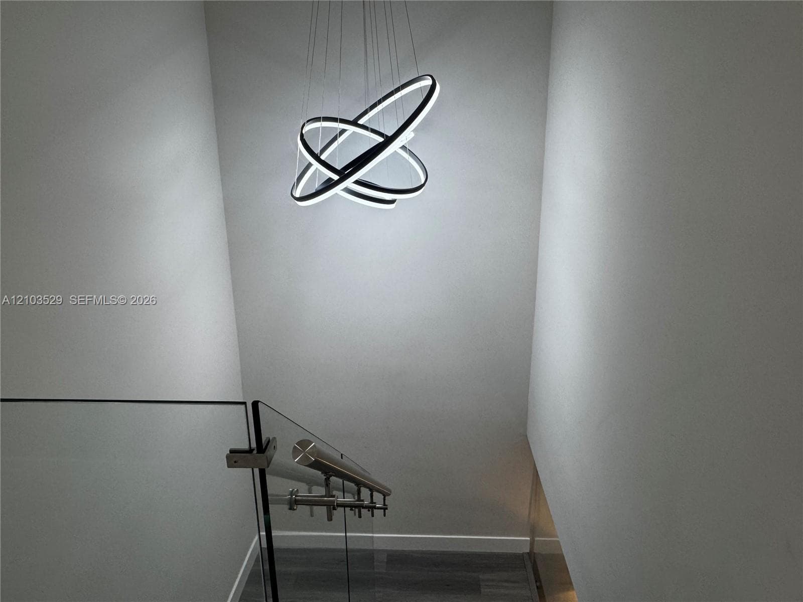 Contemporary multi-ring LED pendant lighting, glass panel staircase railing, and stainless steel handrail