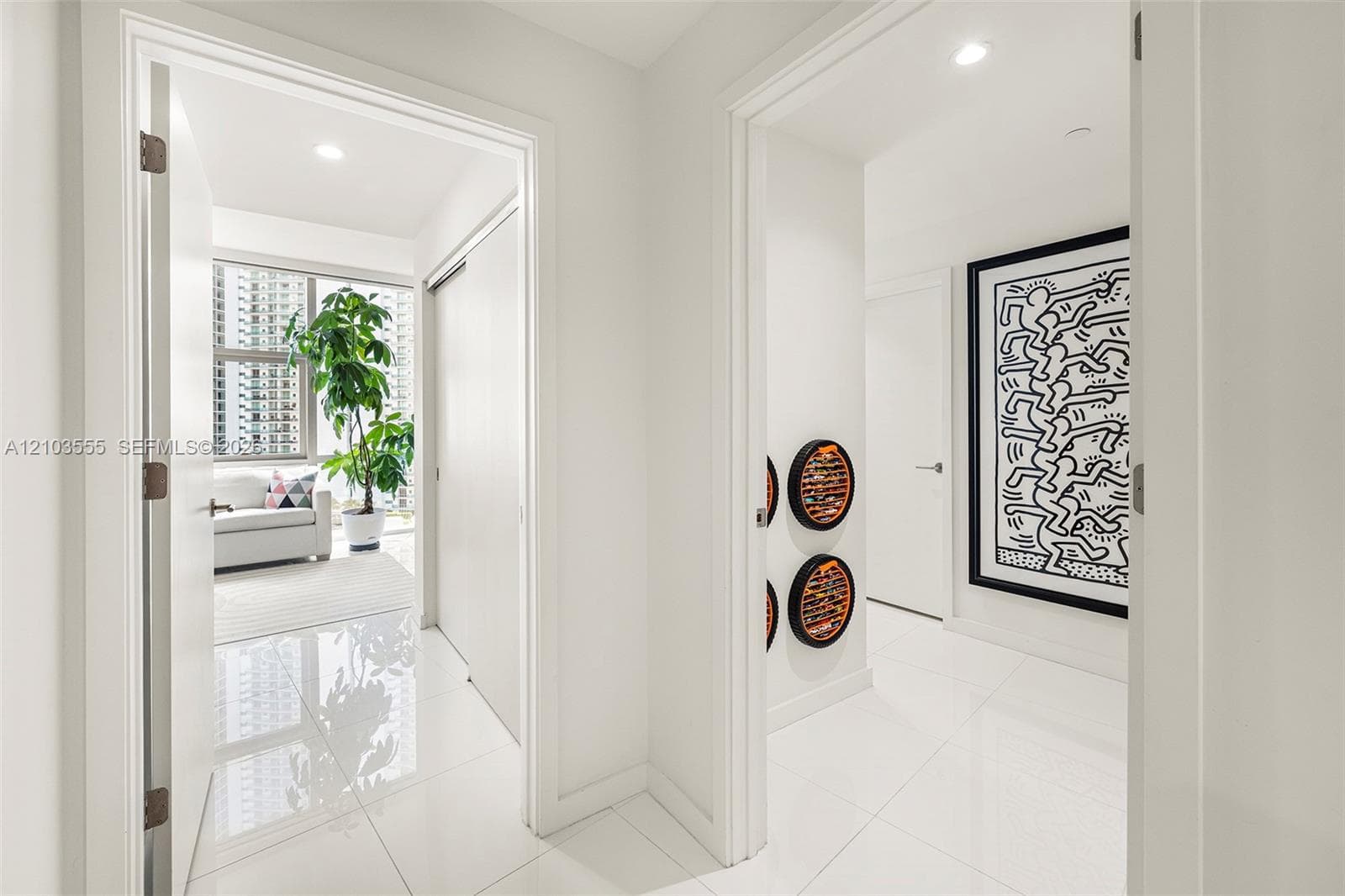 Glossy white tile flooring throughout, recessed ceiling lighting, tall windows, and white walls