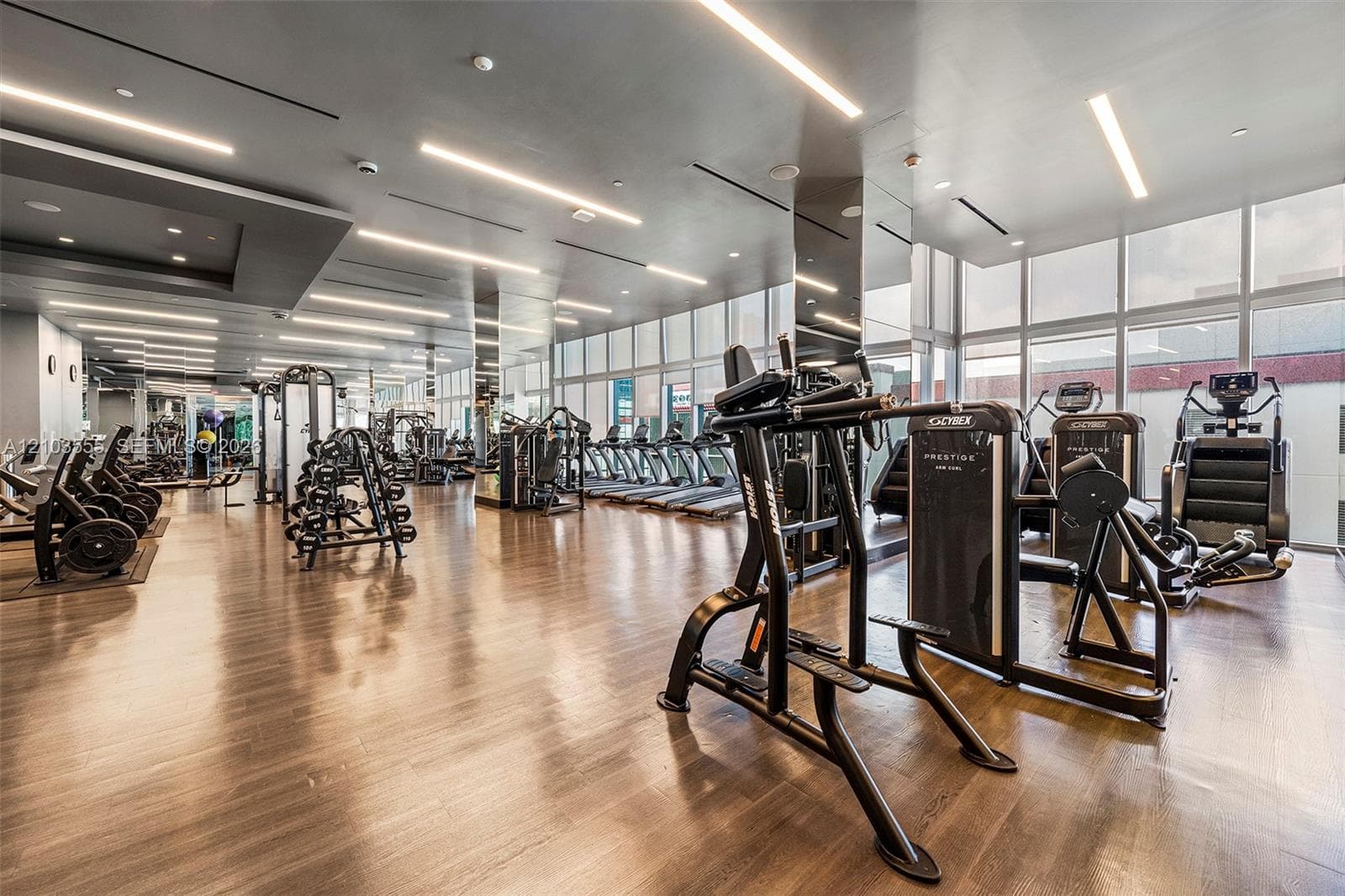 Fitness center featuring wood-finish flooring, high ceilings with recessed lighting, and expansive windows