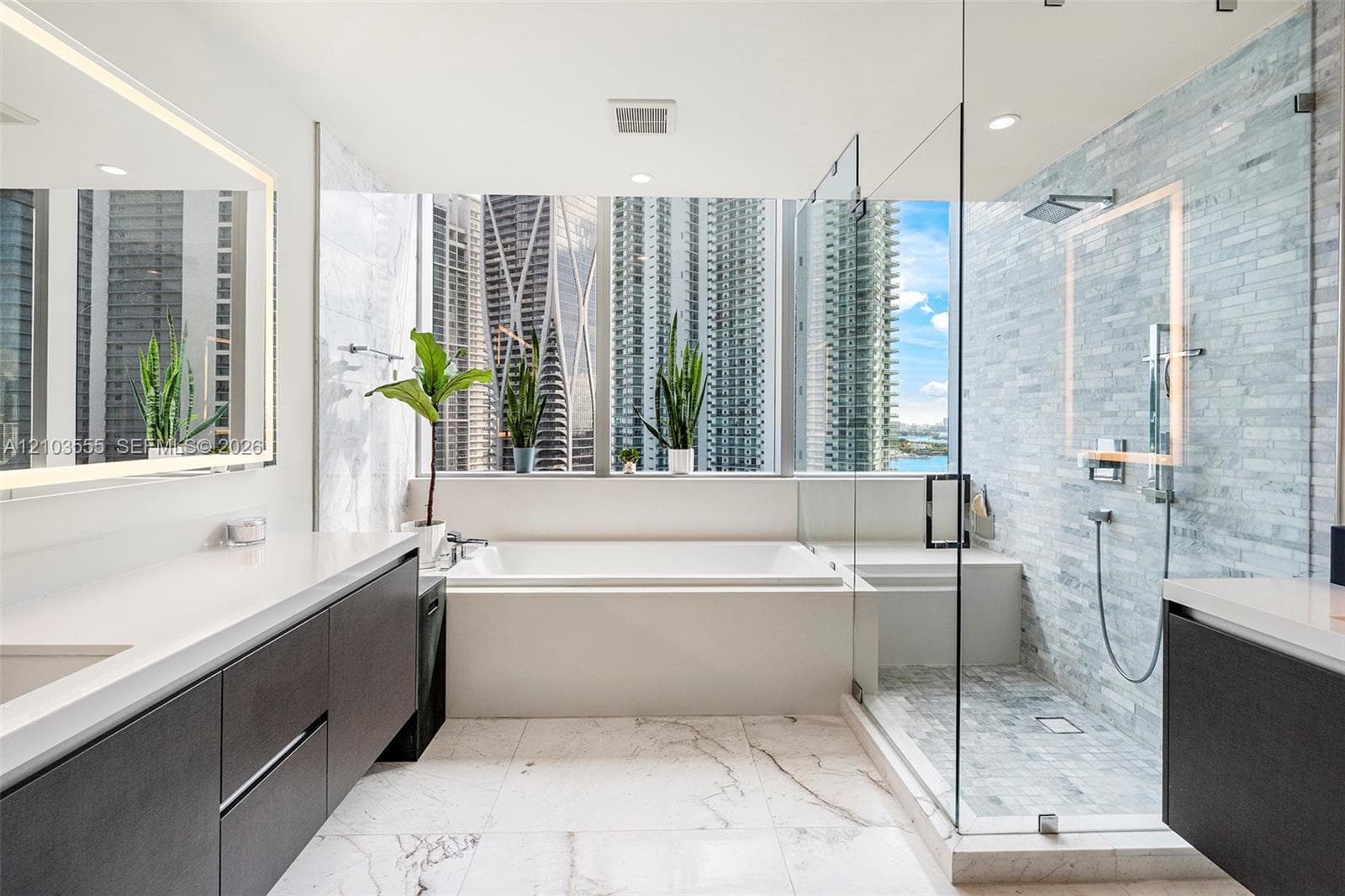 Modern bathroom featuring a built-in soaking tub, a glass-enclosed shower with a tiled wall, and a dual vanity with integrated lighting