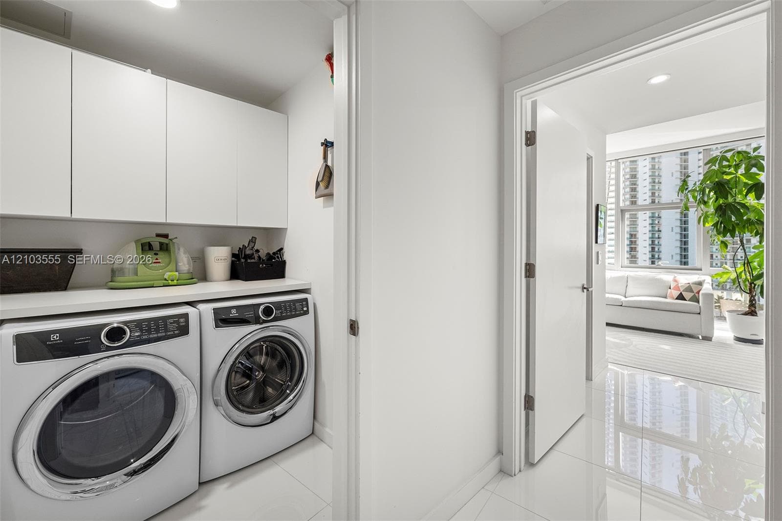 Dedicated laundry area featuring white upper cabinetry, a spacious countertop, and modern front-load washer and dryer