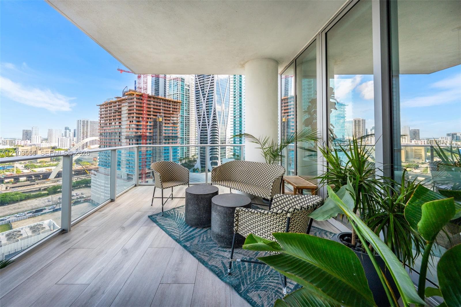 Spacious balcony with tile flooring, glass railings, and expansive glass sliding doors