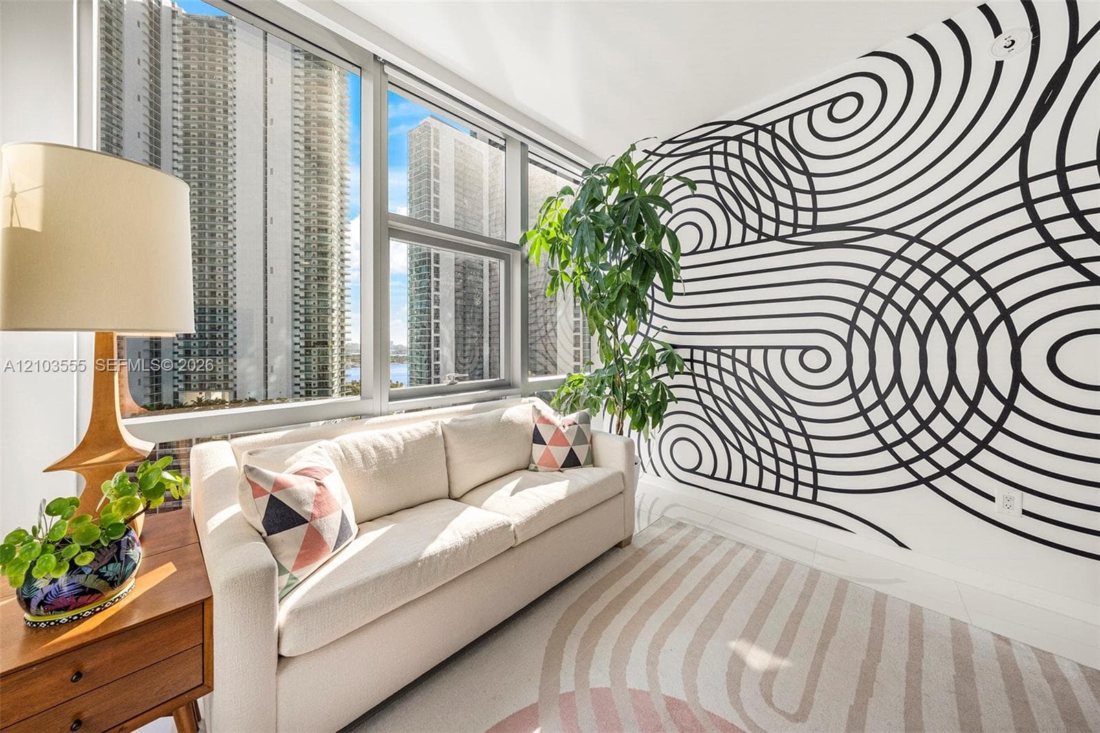 Floor-to-ceiling windows, white walls, and a patterned accent wall