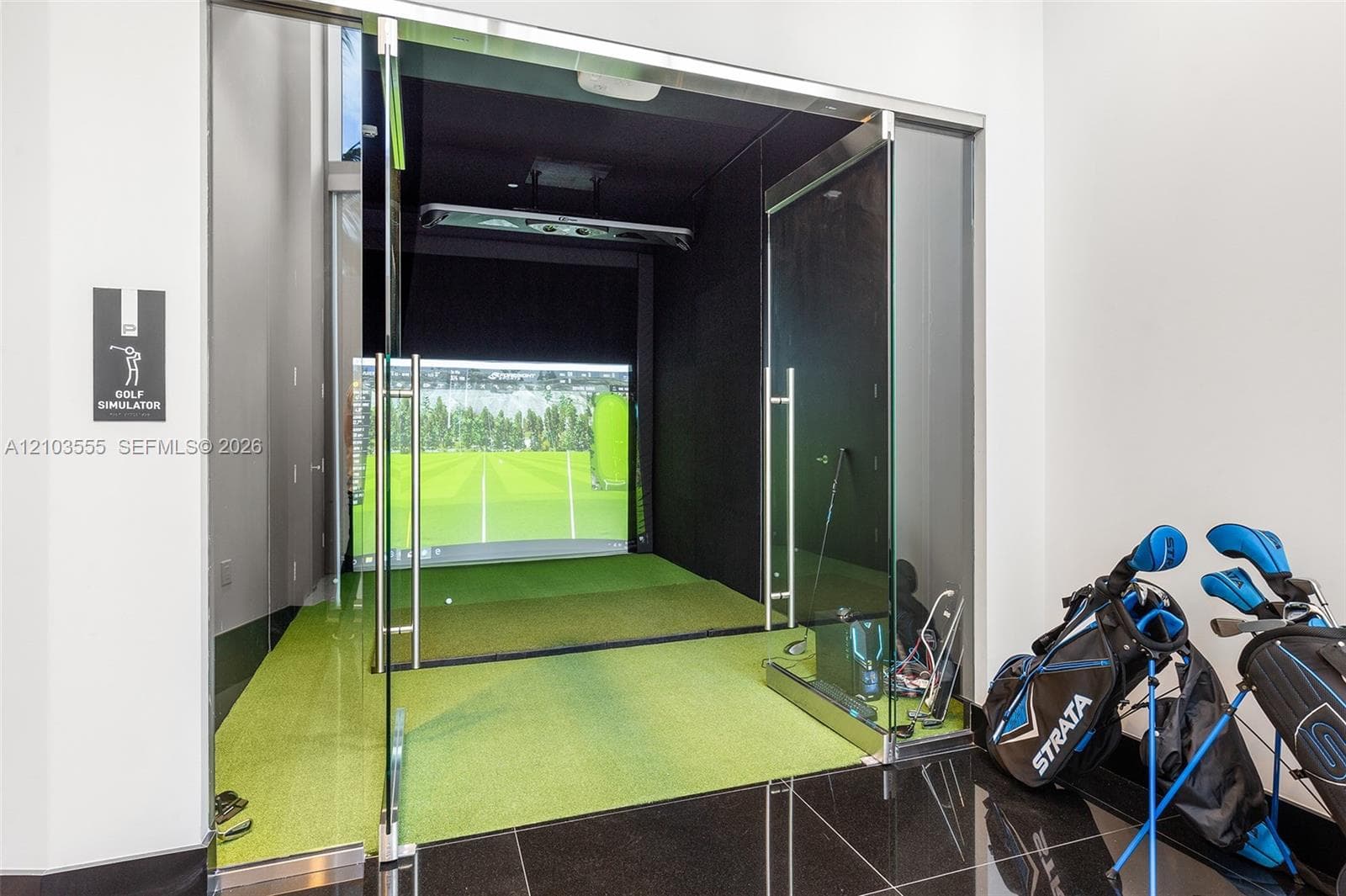 Dedicated golf simulator room featuring a large projection screen and artificial turf
