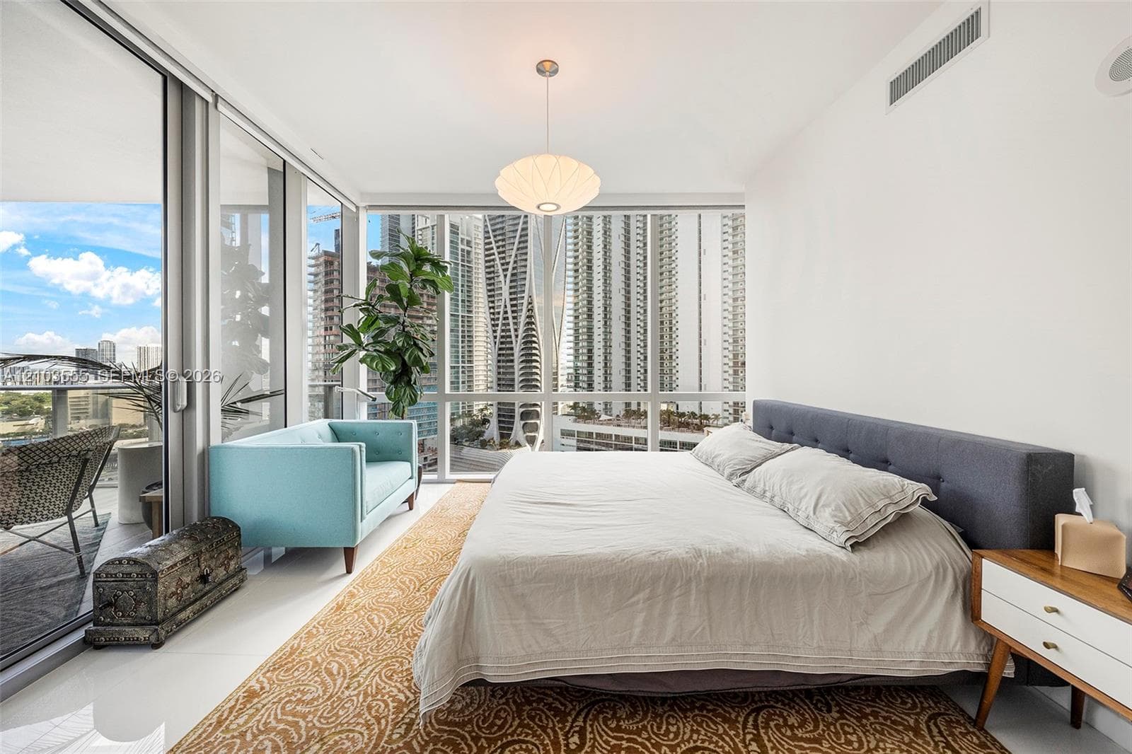 Expansive floor-to-ceiling windows, direct balcony access, contemporary pendant lighting, and bright white walls