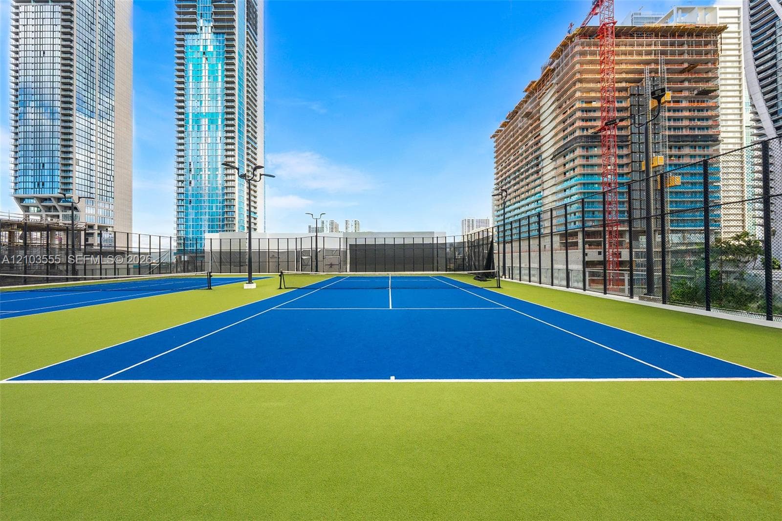 Two multi-color sports courts with perimeter fencing and integrated lighting