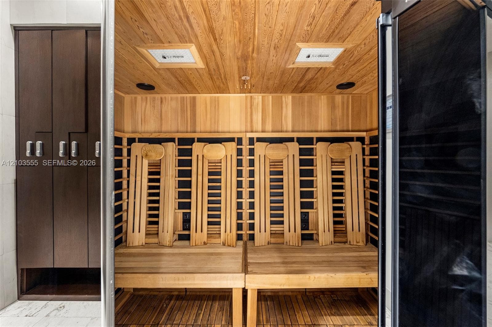 Wood-paneled sauna featuring two built-in benches, slatted backrests, and overhead lighting