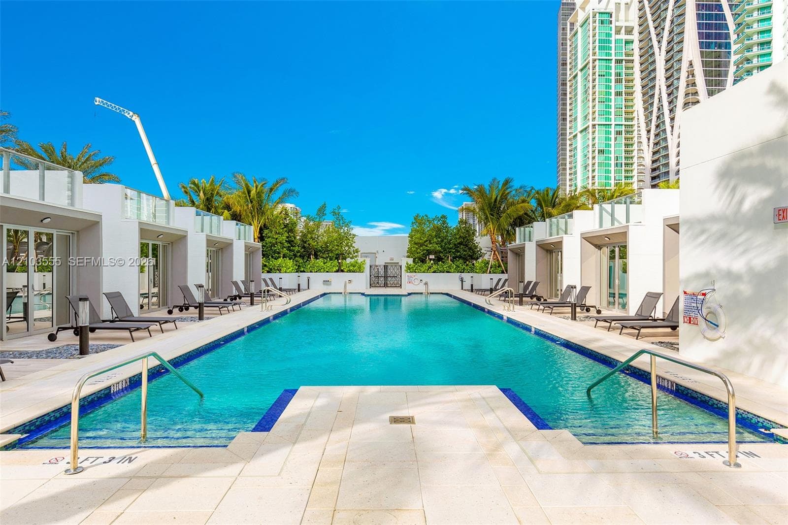 Rectangular swimming pool with integrated steps, surrounded by light-toned paving