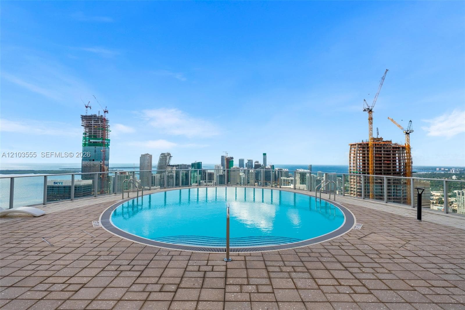 Rooftop pool with paver decking, clear glass panel railing, and metal handrails
