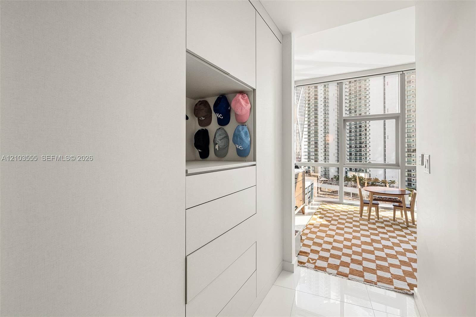 Custom built-in cabinetry with integrated drawers, high-gloss tile flooring, floor-to-ceiling windows, and a fully enclosed balcony
