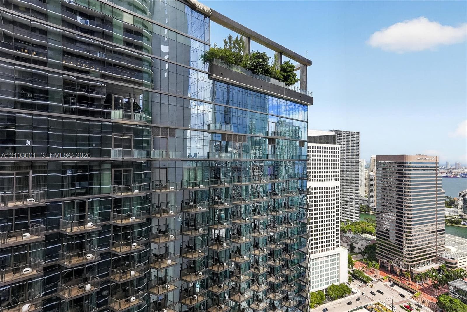 High-rise glass curtain wall architecture featuring repeating cantilevered balconies and a rooftop garden terrace