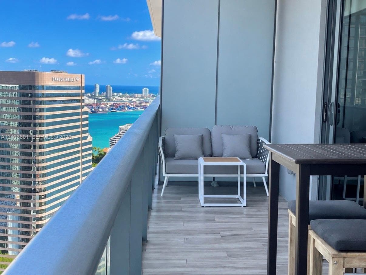 Private balcony featuring wood-finish tile flooring, a glass panel railing, and expansive floor-to-ceiling glass sliding doors