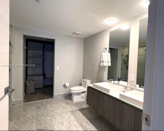 Modern living area featuring wood-finish flooring, a charcoal accent wall, contemporary multi-arm chandelier, and a kitchen island with a stone-surface countertop and undermount sink