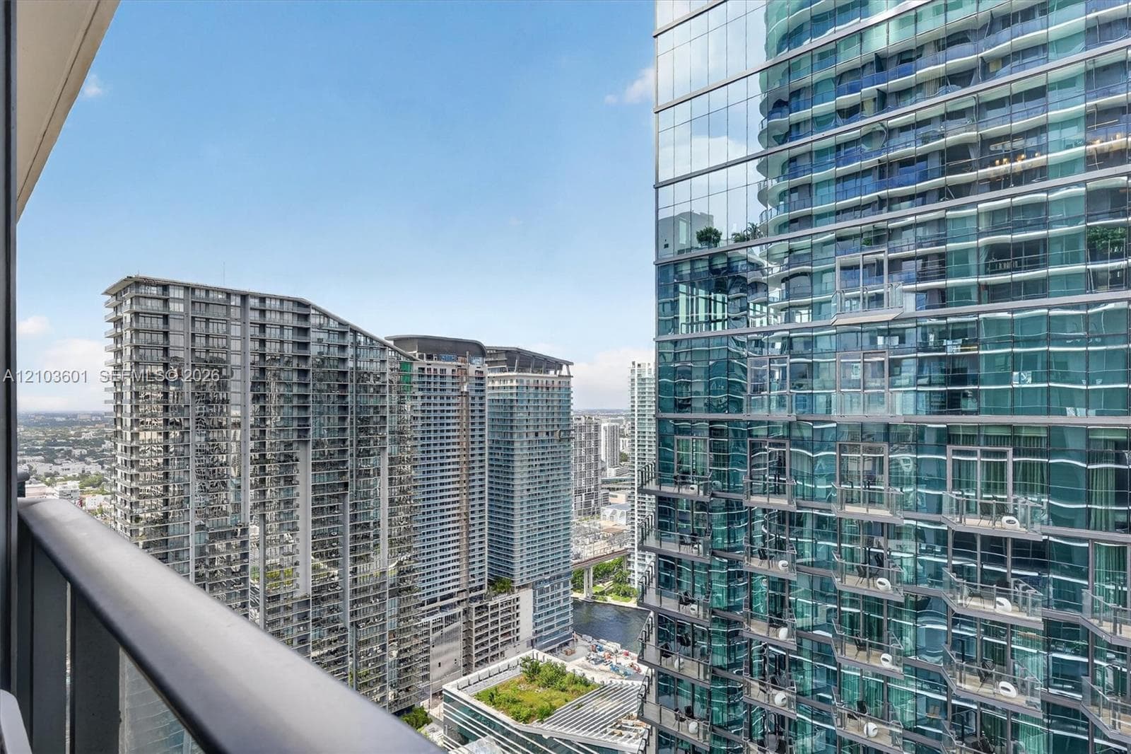 High-rise balcony featuring a metal railing and expansive glass-clad structural surroundings