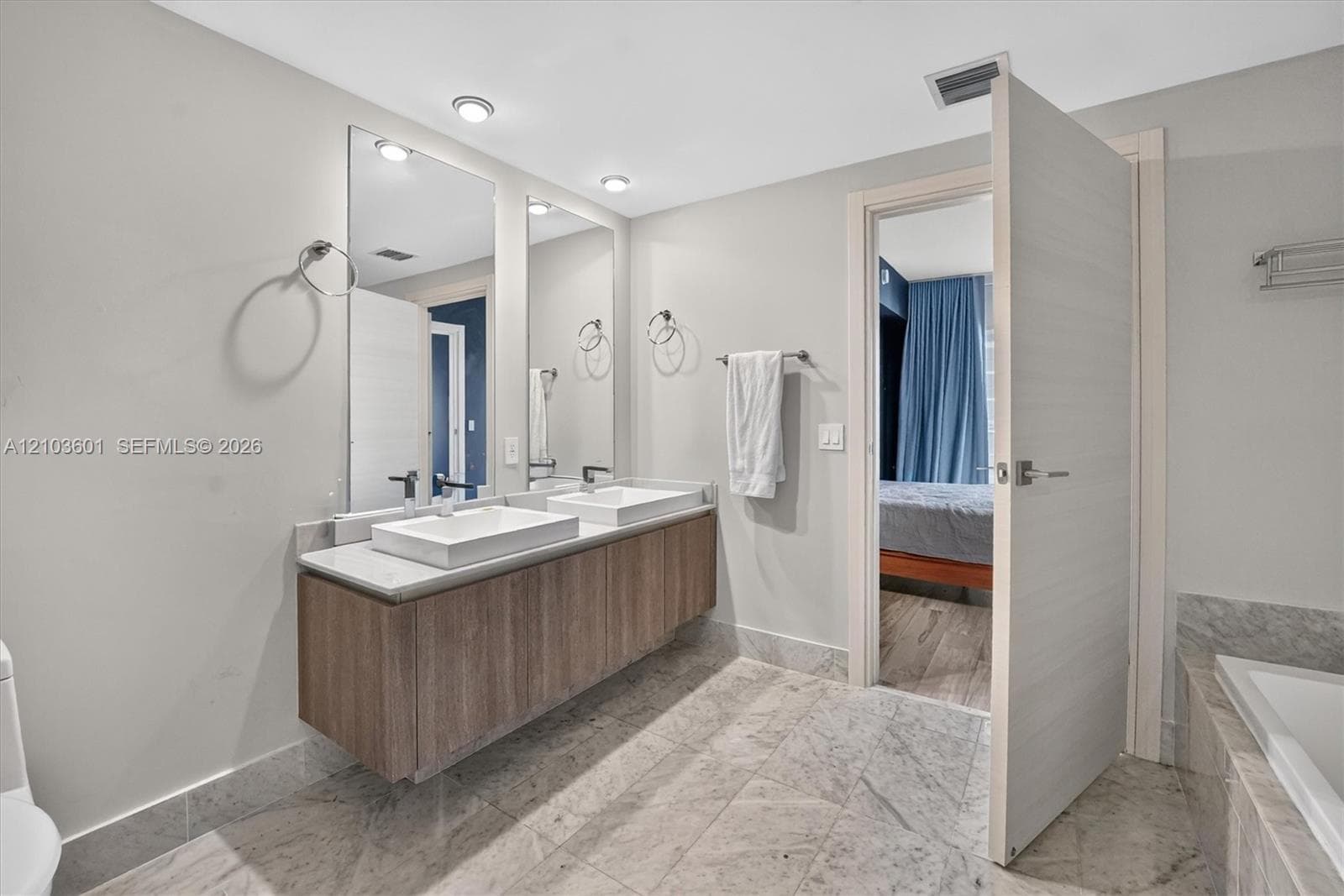Floating dual-sink vanity featuring wood-finish cabinetry, rectangular vessel sinks, stone-finish countertops, and large wall-mounted mirrors